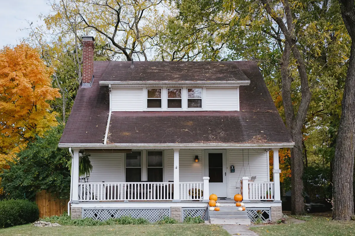 House with a front porch surrounded by autumn trees